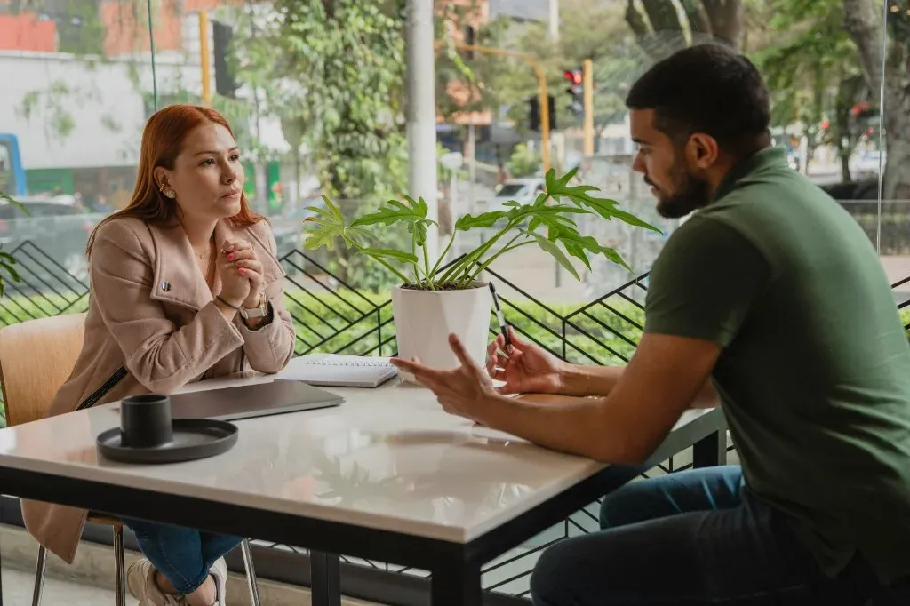 Two colleagues having a professional discussion at a cafe table with a laptop
