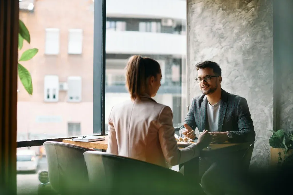 Man and woman reviewing work together on a laptop at a table