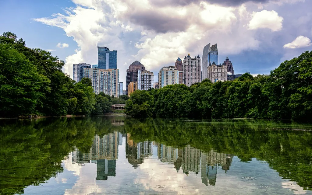 Atlanta skyline reflected in Lake Clara Meer at Piedmont Park with lush green trees