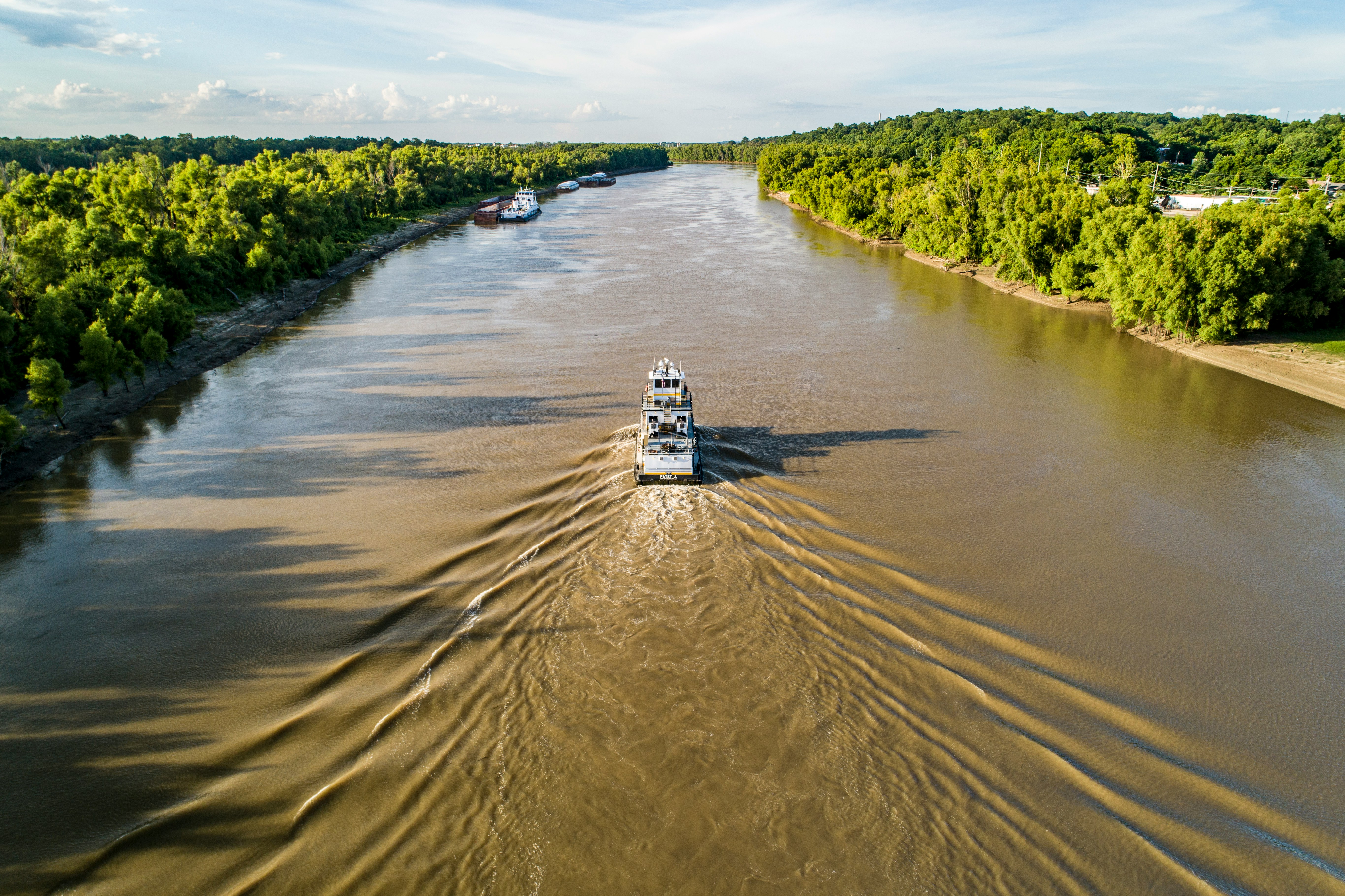 Tugboat traveling down the Mississippi River through lush green banks